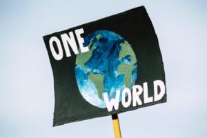 A protestor sign stating 'one world' with a globe at the centre