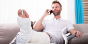 Man with a broken leg recovering on the sofa while talking on the phone