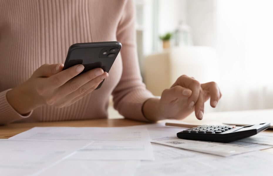 A woman using a phone and calculator.