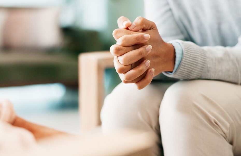 A woman sitting with her hands clasped.