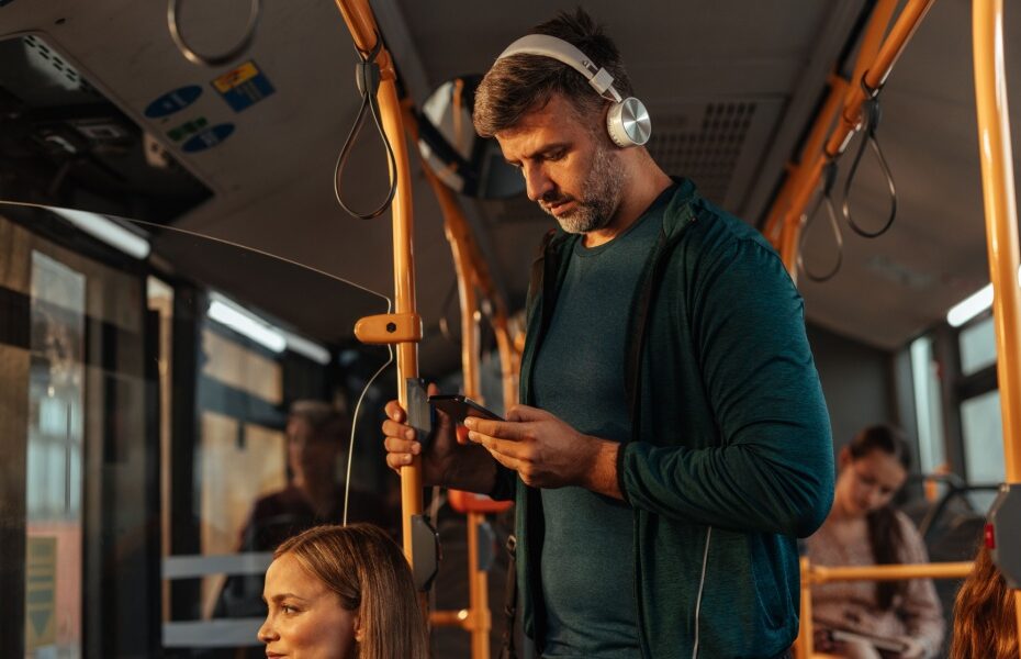 A man travelling on a bus with headphones on.