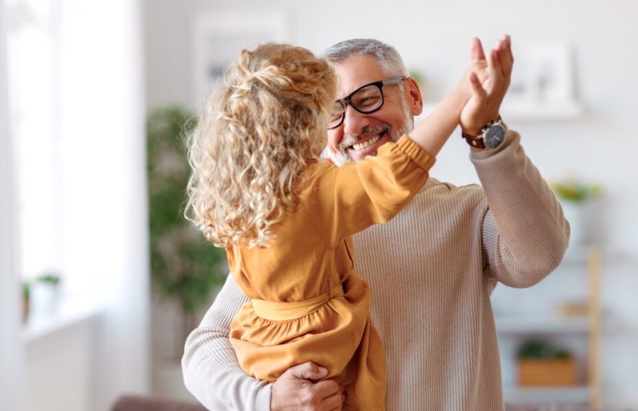A grandfather playing with his granddaughter at home.