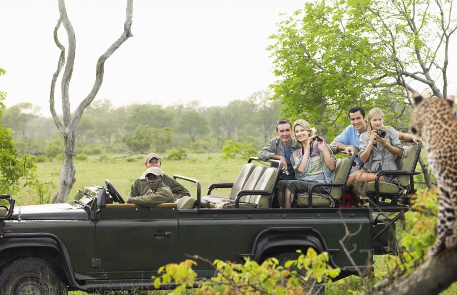 A group of tourists on safari taking a photo of a leopard.