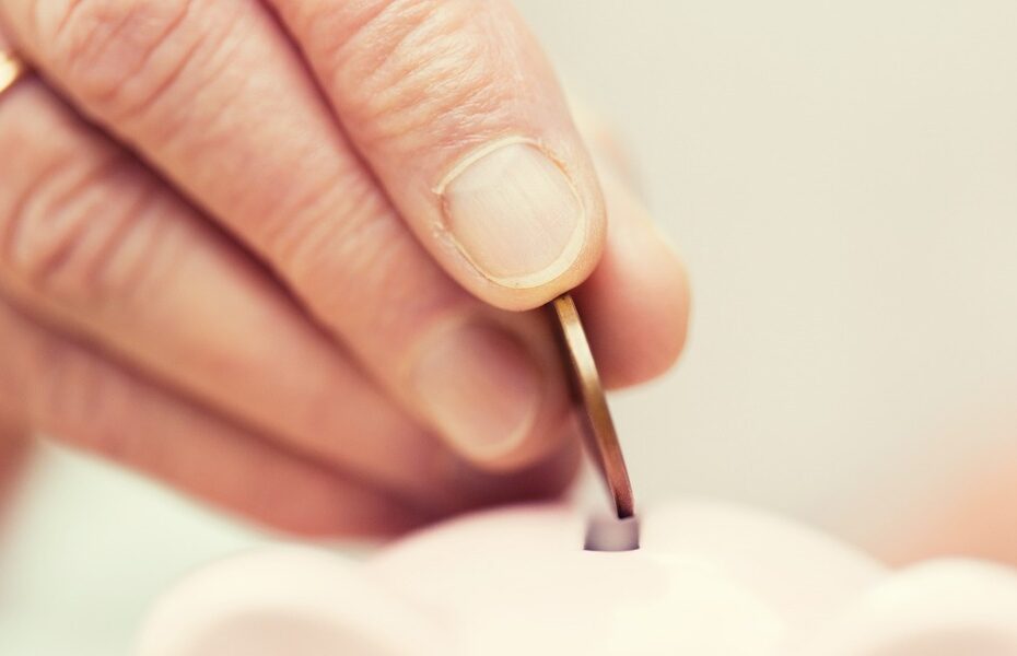 A person putting a coin into a money box.