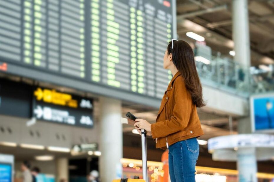 A woman looking at a departure board in an airport.