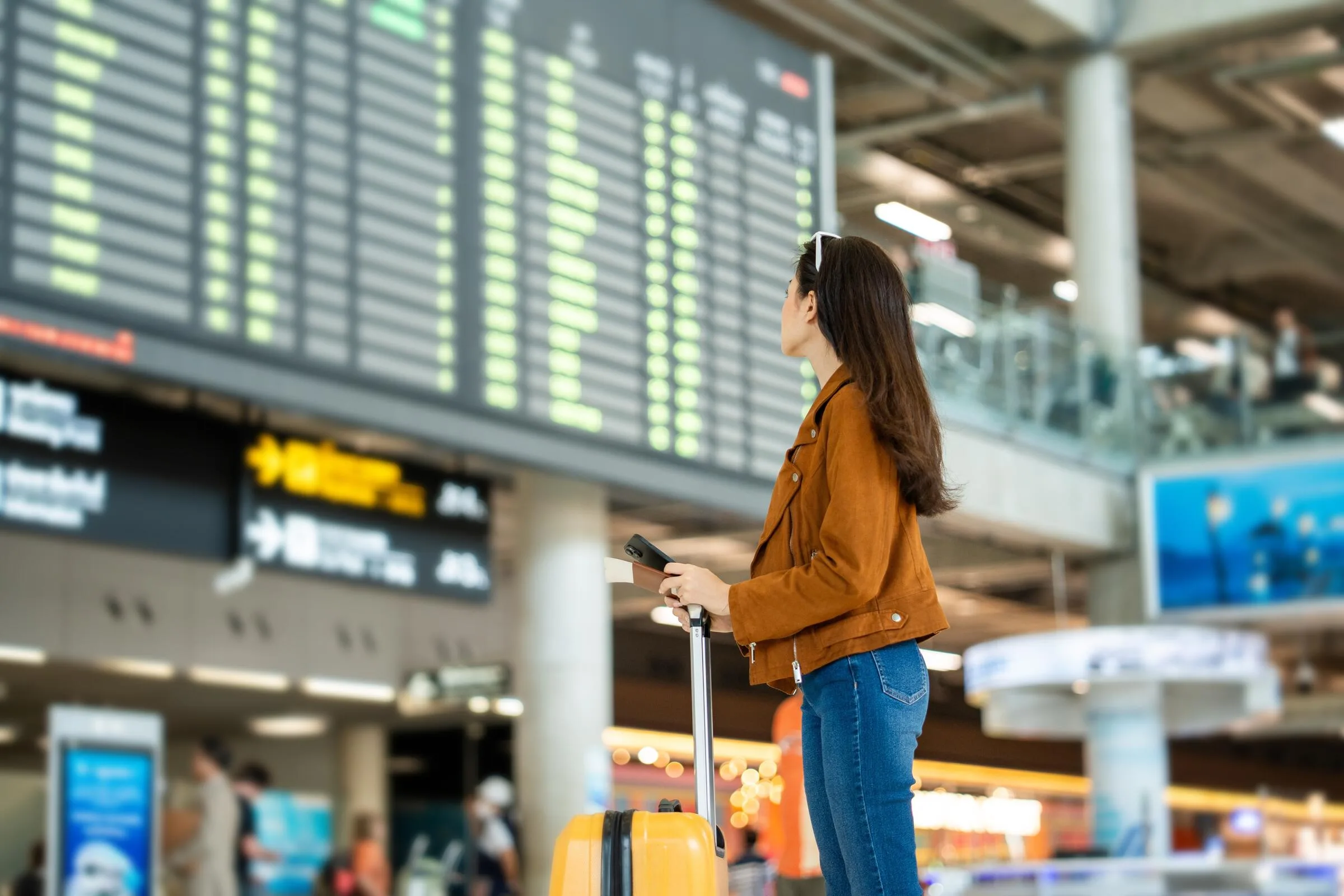 A woman looking at a departure board in an airport.