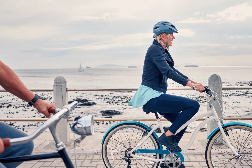 A woman cycling along a beachfront.
