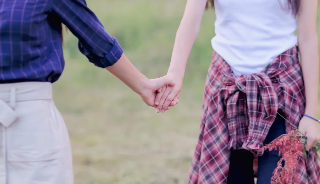Two women holding hands.