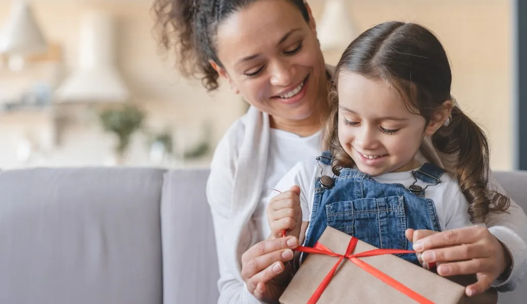 A mother and daughter unwrapping a gift.