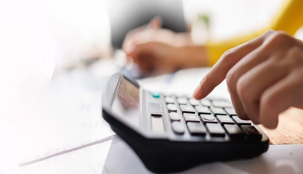 A person using a calculator while reviewing paperwork.
