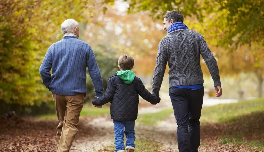 A grandfather walking with his son and grandchild.