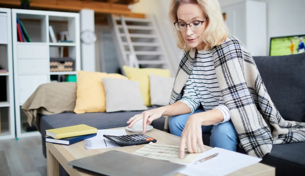 A middle-aged woman using a calculator and looking at financial paperwork