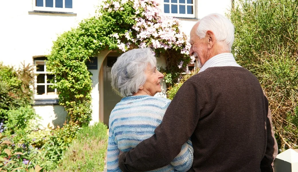 Rear view of senior couple outside pretty cottage